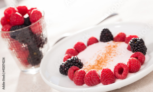 breakfast of raspberries and blackberries with yogurt on table