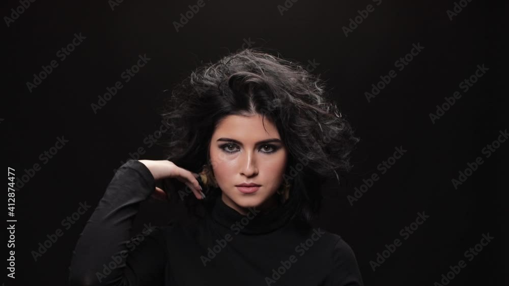 beautiful girl looking at camera in studio, close up. Curly hair fashion model with dark make-up posing on black background. beautiful girl looking at camera in studio, close up. Curly hair fashion model with dark make-up posing on black background.