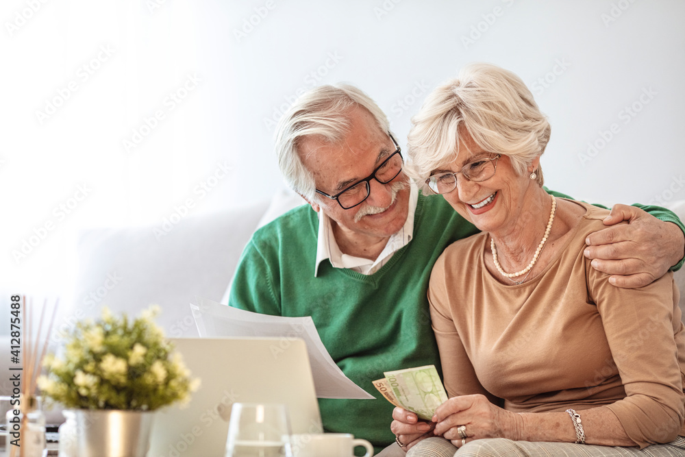 Mature couple doing family finances at home. Senior couple discussing home economics sitting at table. Happy couple sitting at home planning household financials. Mature couple doing family finances at home. Senior couple discussing home economics sitting at table. Happy couple sitting at home planning household financials.