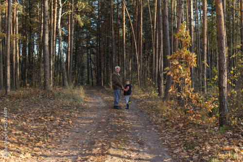 Happy child with Grandfather playing at the forest. Grandpa retiree. Retirement parent. Portrait of pensive senior man and his grandson. Senior man having fun with his grandchild outdoor.