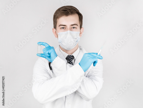 Biological hazard. Chinese coronavirus epidemic. A man in a medical gown and mask holds an injection syringe and a vaccine. Vaccine against influenza  coronavirus  Ebola  tuberculosis.
