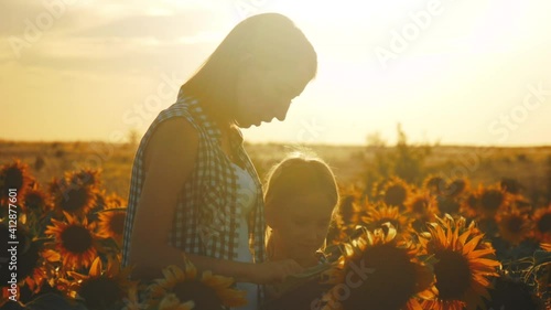 A family farmer with a tablet in the field. Pretty female farmer and her beautiful daughter talk about sunflower in the field. Family travels through a blooming sunflower plantation. Farming concept. photo
