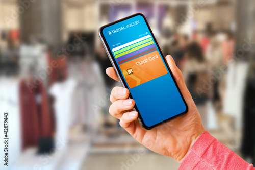 Woman using digital wallet on her mobile phone to pay wirelessly in store with her credit card