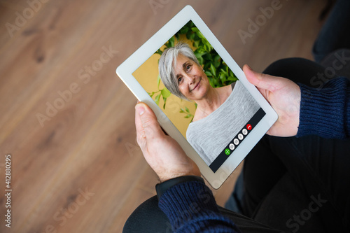 Screen shot of a remote mother son video call with the tablet - Woman speaking with the man separated from the lockdwon by Coronavirus Covid-19 - Millennials meet online a loved one who lives far away photo