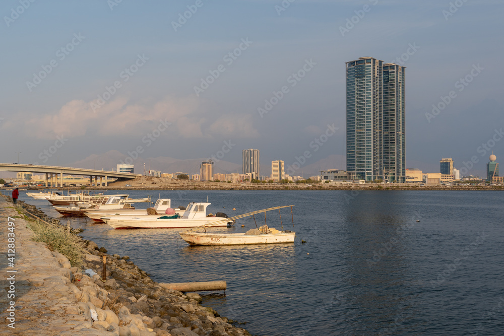 Ras Al Khaimah City in the United Arab Emirates pan on a cloudy day with boats and bridge and Julphur Towers in view.