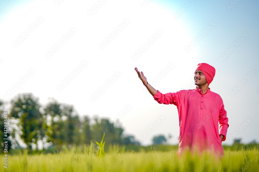 Young indian farmer standing his wheat field and giving happy expression Young indian farmer standing his wheat field and giving happy expression