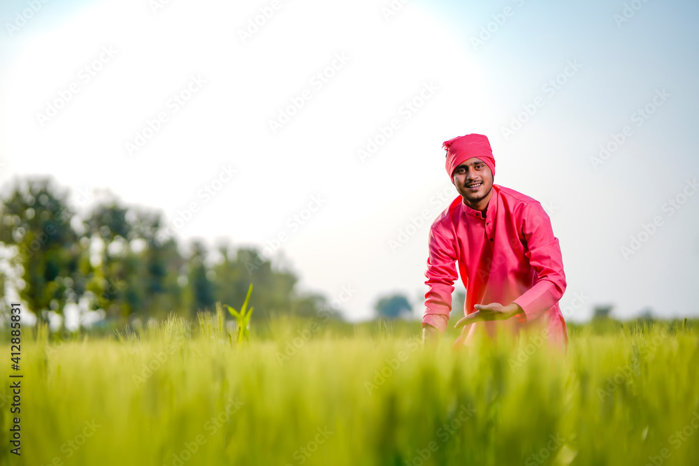 Young indian farmer standing his wheat field and giving happy expression Young indian farmer standing his wheat field and giving happy expression