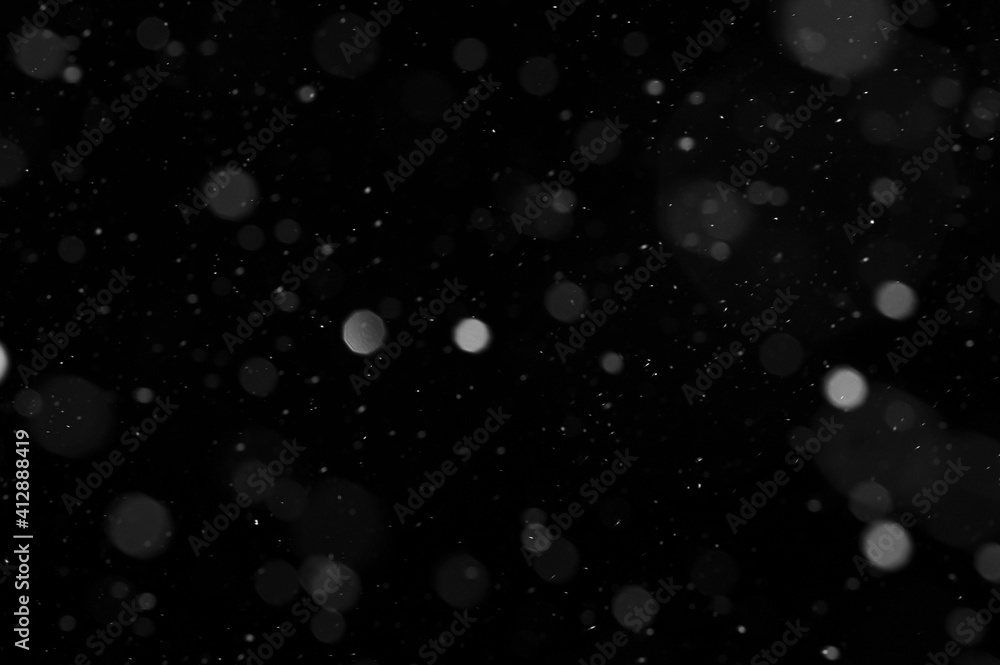 Bokeh of white snow on a black background. Snowfall - design element.