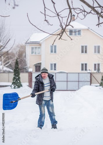 Snow collapse, man cleaning snow at winter weather with a shovel on a yard, winter trouble concept