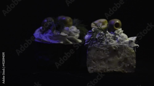 Delicious dessert. Creamy muffins with ham and olives and garlic. Backlit with light. 4K. On a black background.