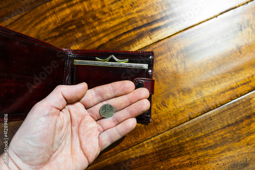 The hand of an adult holds Russian five kopeks coin in the palm of his hand and opened wallet. photo