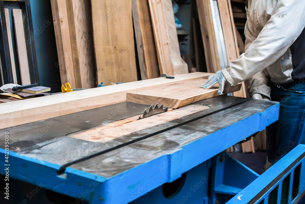 a man cuts a board on a stationary circular saw in a carpentry workshop a man cuts a board on a stationary circular saw in a carpentry workshop