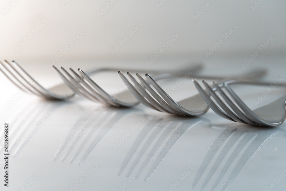 Row of Forks on white marble texture background. Concept for food and dining tableware Row of Forks on white marble texture background. Concept for food and dining tableware