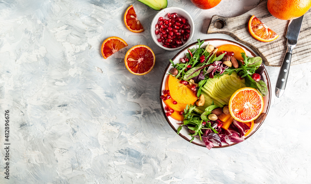 Healthy vegan lunch Buddha bowl. Avocado, avocado, persimmon, blood orange, nuts, spinach, arugula and pomegranate. vegetables salad. Long banner format Top view Healthy vegan lunch Buddha bowl. Avocado, avocado, persimmon, blood orange, nuts, spinach, arugula and pomegranate. vegetables salad. Long banner format Top view