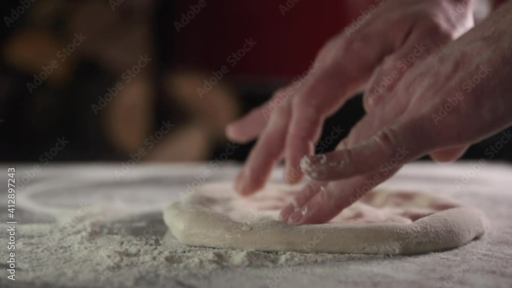 From the dough form a blank for a round pizza. The dough is tossed over the surface of the table and stretched by hand in slow motion and in good light. From the dough form a blank for a round pizza. The dough is tossed over the surface of the table and stretched by hand in slow motion and in good light.