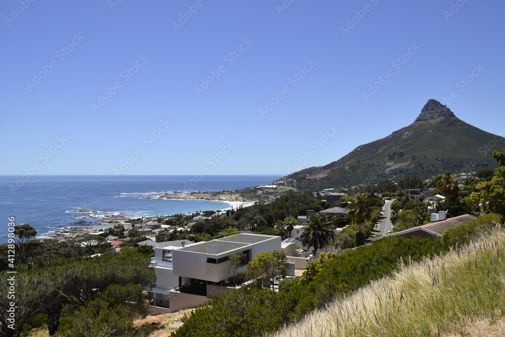 View of some houses, Camps Bay Beach and Lion's Head from the slopes of Table Mountain in Kasteelspoort hike. Cape Town, South Africa.