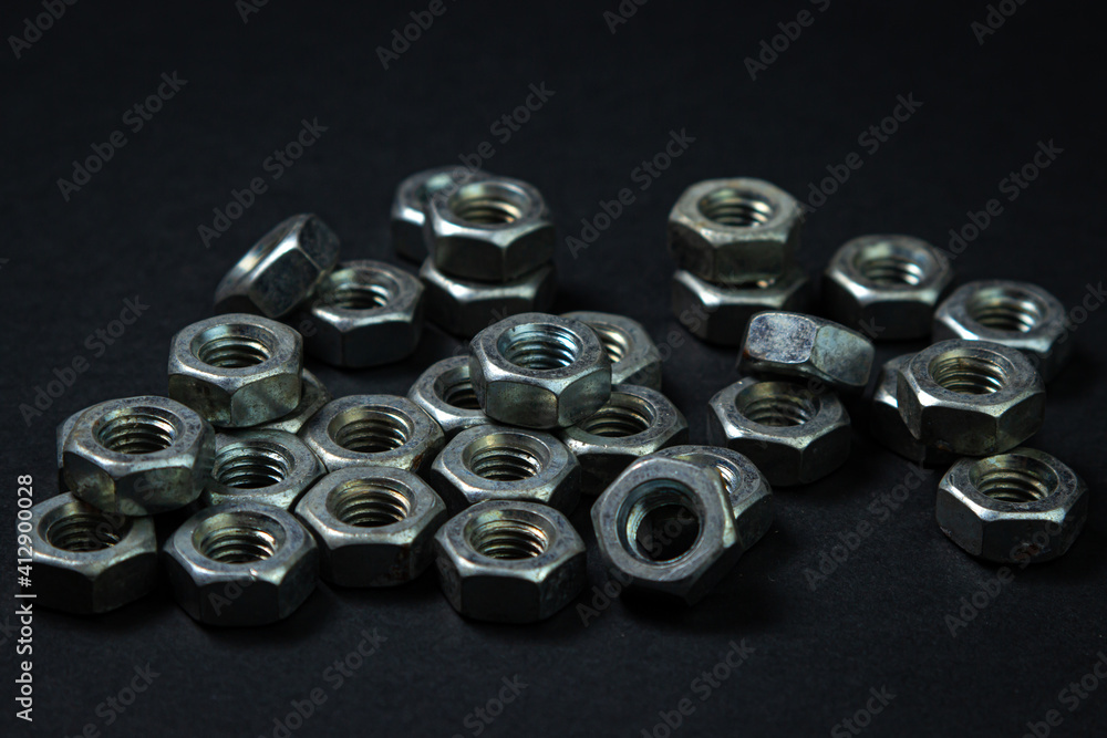 Nut bolts on a black background. threaded fastener. The nut bolts are scattered on the black surface. Nut bolts on a black background. threaded fastener. The nut bolts are scattered on the black surface.