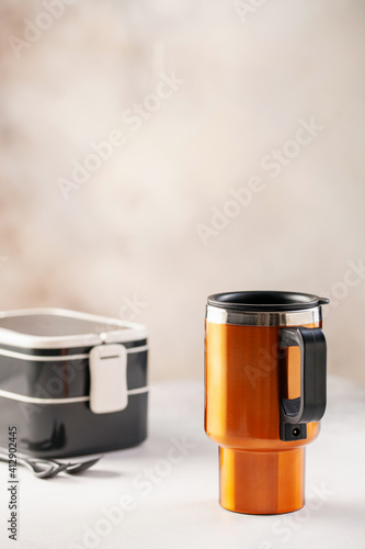 Reusable coffee mug and a plastic food container on a bright background. Healthy break. Reusable ware. Zero waste concept