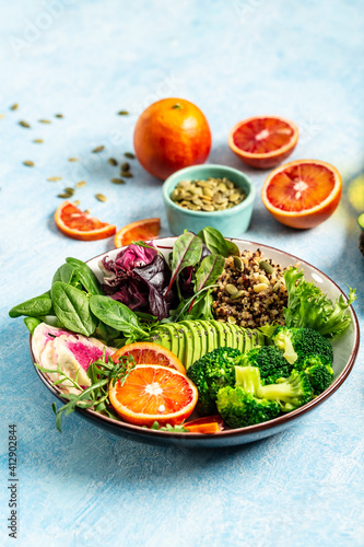 Vegan, detox Buddha bowl with vegetables, avocado, blood orange, broccoli, watermelon radish, spinach, quinoa, pumpkin seeds. Balanced food. Delicious detox diet. Top view. vertical image