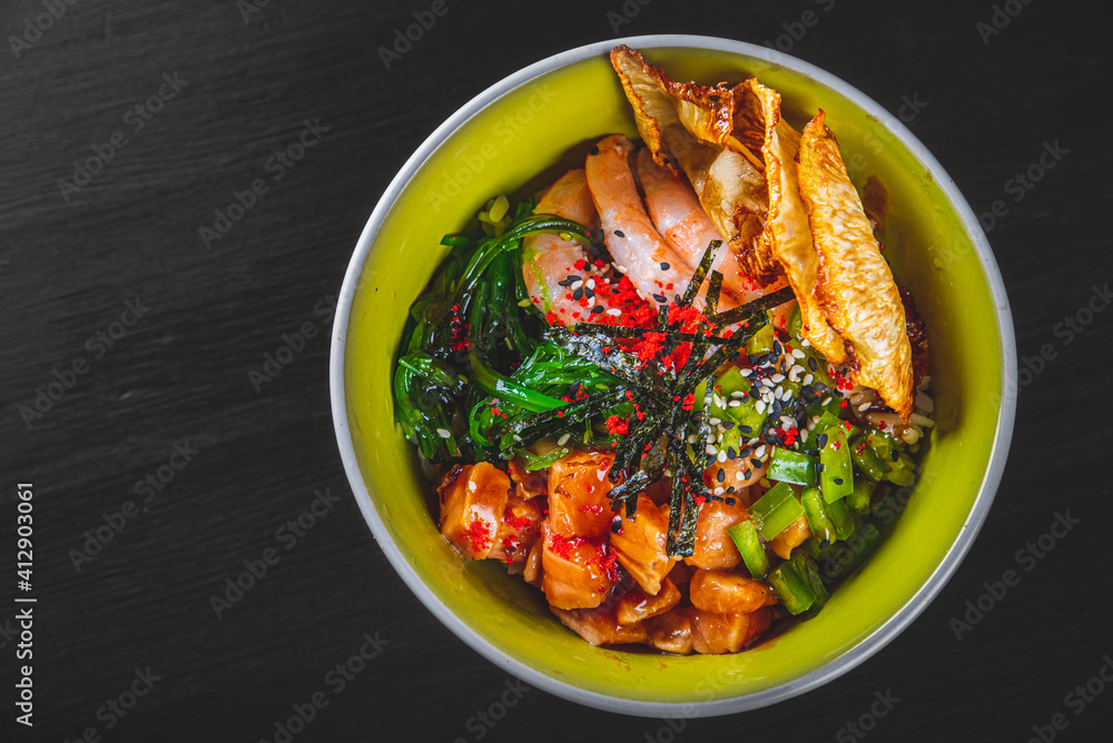 Fresh seafood recipe. Shrimp salmon poke in bowl on black wooden table background Fresh seafood recipe. Shrimp salmon poke in bowl on black wooden table background