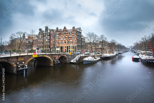 Winter snow view of Dutch canal and old houses in the historic city of Amsterdam  the Netherlands