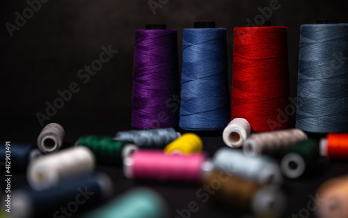 Multi-colored threads are scattered on a dark background. Selective focus
