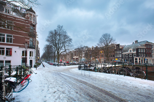 Winter snow view of Dutch canal and old houses in the historic city of Amsterdam, the Netherlands