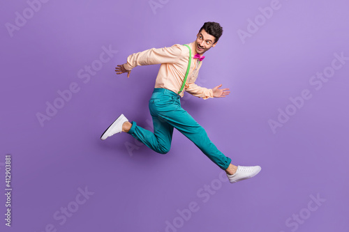 Full length profile side photo of gentleman jump run empty space wear blue pants isolated on violet color background