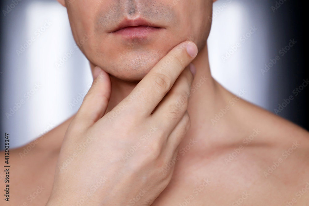 Fototapeta premium Man touching his shaved chin, beauty and skin care concept. Male face and neck close up