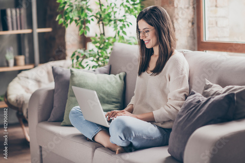 Photo of charming positive woman sit couch living room work laptop wear glasses write inside house indoors