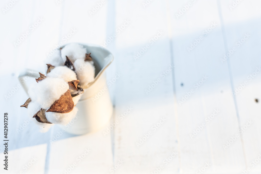Light and airy cotton in a vase on white farm table Light and airy cotton in a vase on white farm table