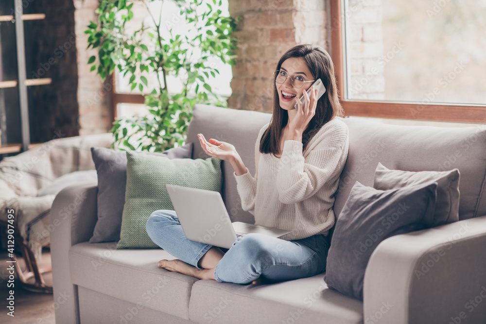Photo of charming happy girl sit living room couch speak phone relax inside house wear sweater jeans indoors home Photo of charming happy girl sit living room couch speak phone relax inside house wear sweater jeans indoors home