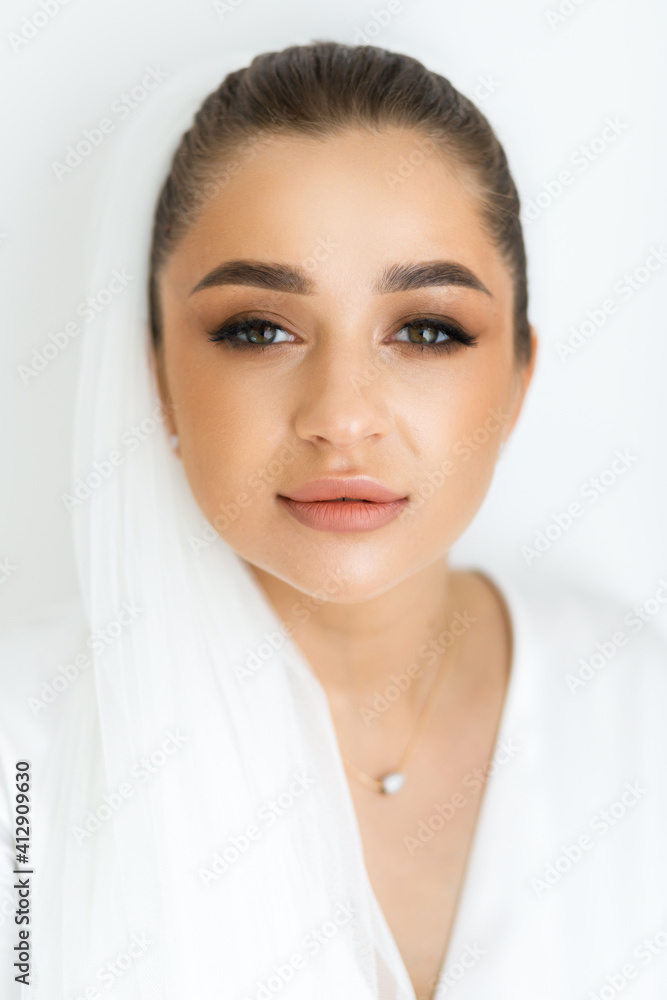 Morning of the bride in a white robe and a veil in the room. Beautiful luxurious bride Morning of the bride in a white robe and a veil in the room. Beautiful luxurious bride