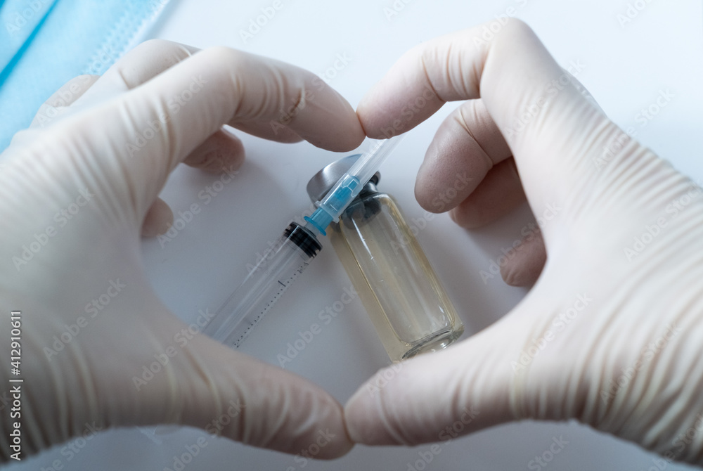 vials with infection vaccine, syringe, mask. heart with hands in protective gloves vials with infection vaccine, syringe, mask. heart with hands in protective gloves