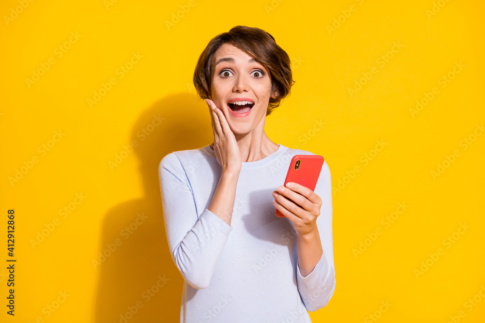Photo of impressed sweet young lady dressed white shirt arm cheek holding modern gadget isolated yellow color background Photo of impressed sweet young lady dressed white shirt arm cheek holding modern gadget isolated yellow color background