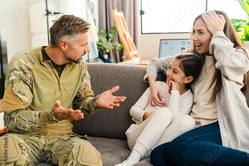 Masculine military man gesturing while talking his happy family