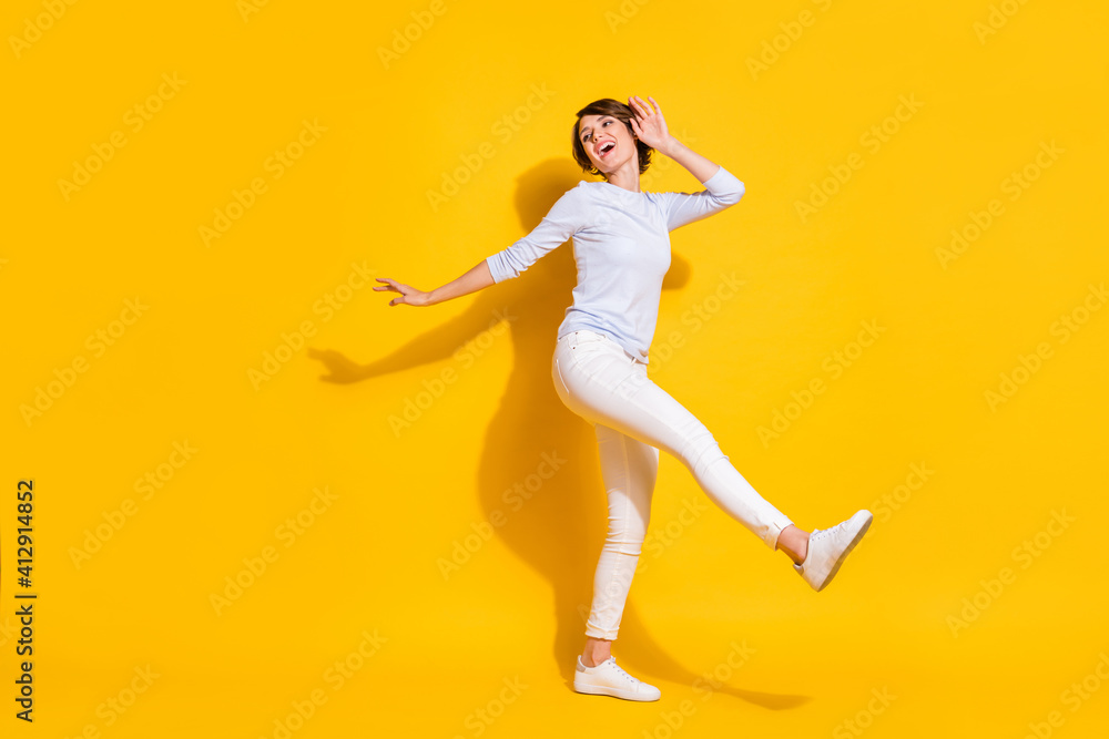 Full length photo of funny adorable young woman wear white shirt dancing walking isolated yellow color background