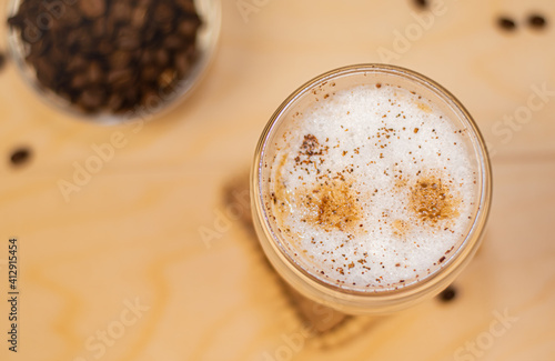 Coffee in a glass thermostat on a wooden tray. Wooden background with a cup of cappuccino and coffee beans photo