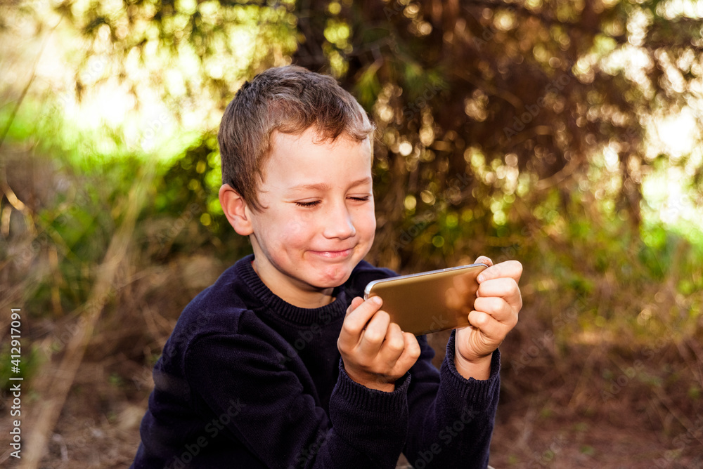 Happy child plays with his mobile phone during an excursion to nature. Happy child plays with his mobile phone during an excursion to nature.
