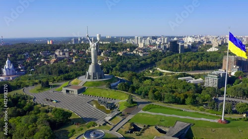 Flying a drone to the famous monument in Ukraine Motherland. Cinematic aerial view to the Motherland statue in the Kiev and national flag. Ukraine.  Monument of the Motherland in Kiev. photo