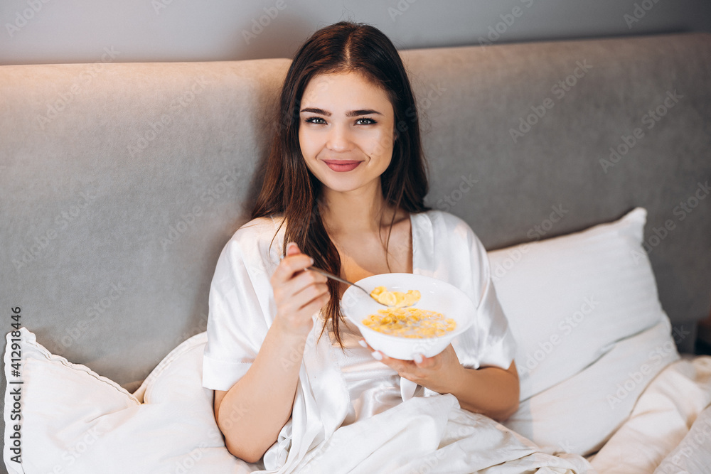 cornflakes for breakfast in bed. beautiful woman holding a plate of cornflakes in bed cornflakes for breakfast in bed. beautiful woman holding a plate of cornflakes in bed