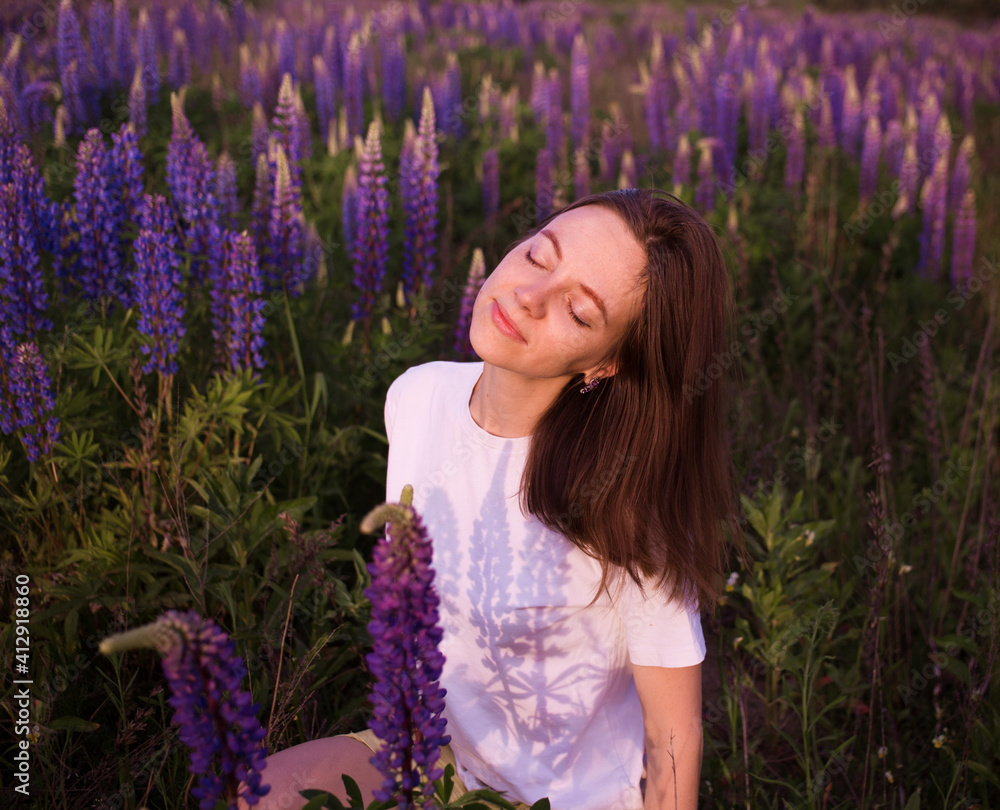 Beautiful woman with closed eyes among purple wildflowers of lupins in the meadow. Sensual female portrait in nature. digital detox, summer weekend, enjoy the moment Beautiful woman with closed eyes among purple wildflowers of lupins in the meadow. Sensual female portrait in nature. digital detox, summer weekend, enjoy the moment