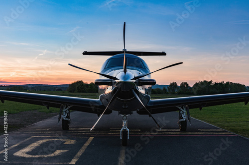 Obraz na płótnie A single-engine plane is parked on the runway, bathed in the evening sun. Beautiful color view of the plane. w salonie