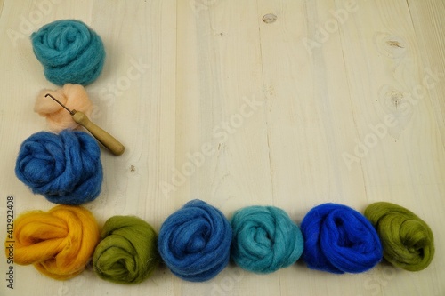 Skeins of multicolored yarn for felting lies on a white wooden board