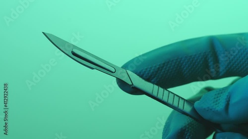 Soft shot of her hand showing a medical scalpel up close