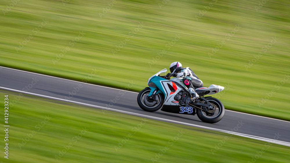 A panning shot of a racing motorbike as it circuits a track.