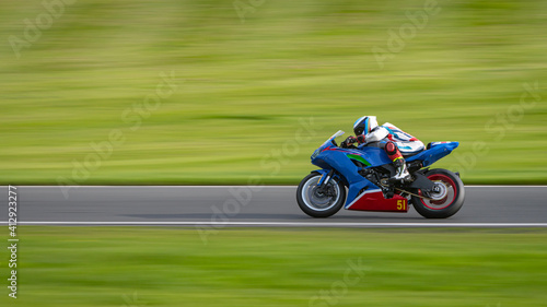 A panning shot of a racing motorbike as it circuits a track.