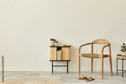 Neutral concept of living room interior with design wooden chair, round carpet, stool, cabinet, slippers, decoration and elegant personal accessories. Template. Copy space. photo