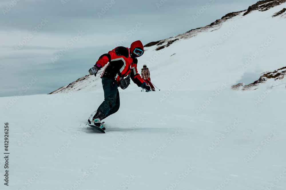 Man snowboarder rides downhill on a snowboard in the Alpine mountains. Winter sports and recreation. Man snowboarder rides downhill on a snowboard in the Alpine mountains. Winter sports and recreation.