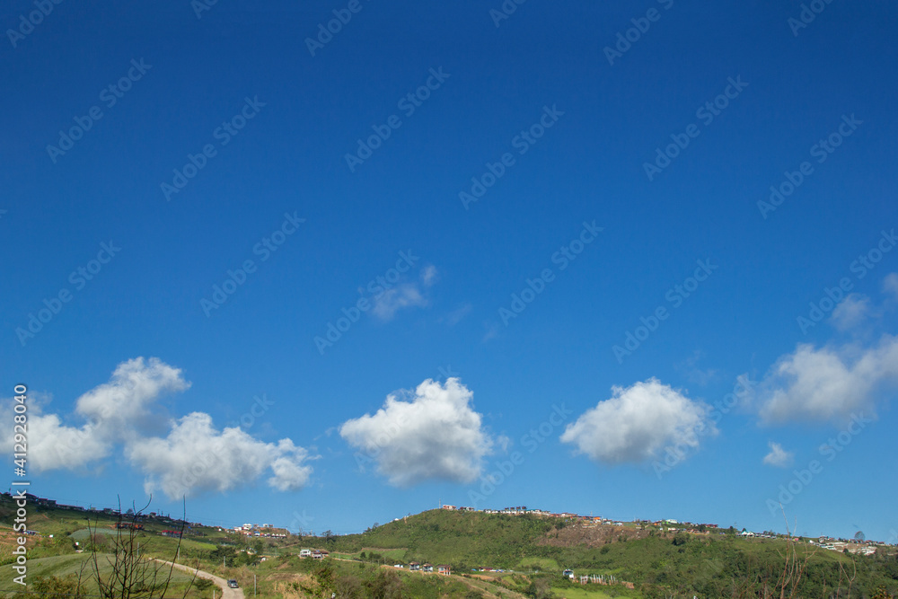 Bright blue sky gold with beautiful clouds and green grass mountains.